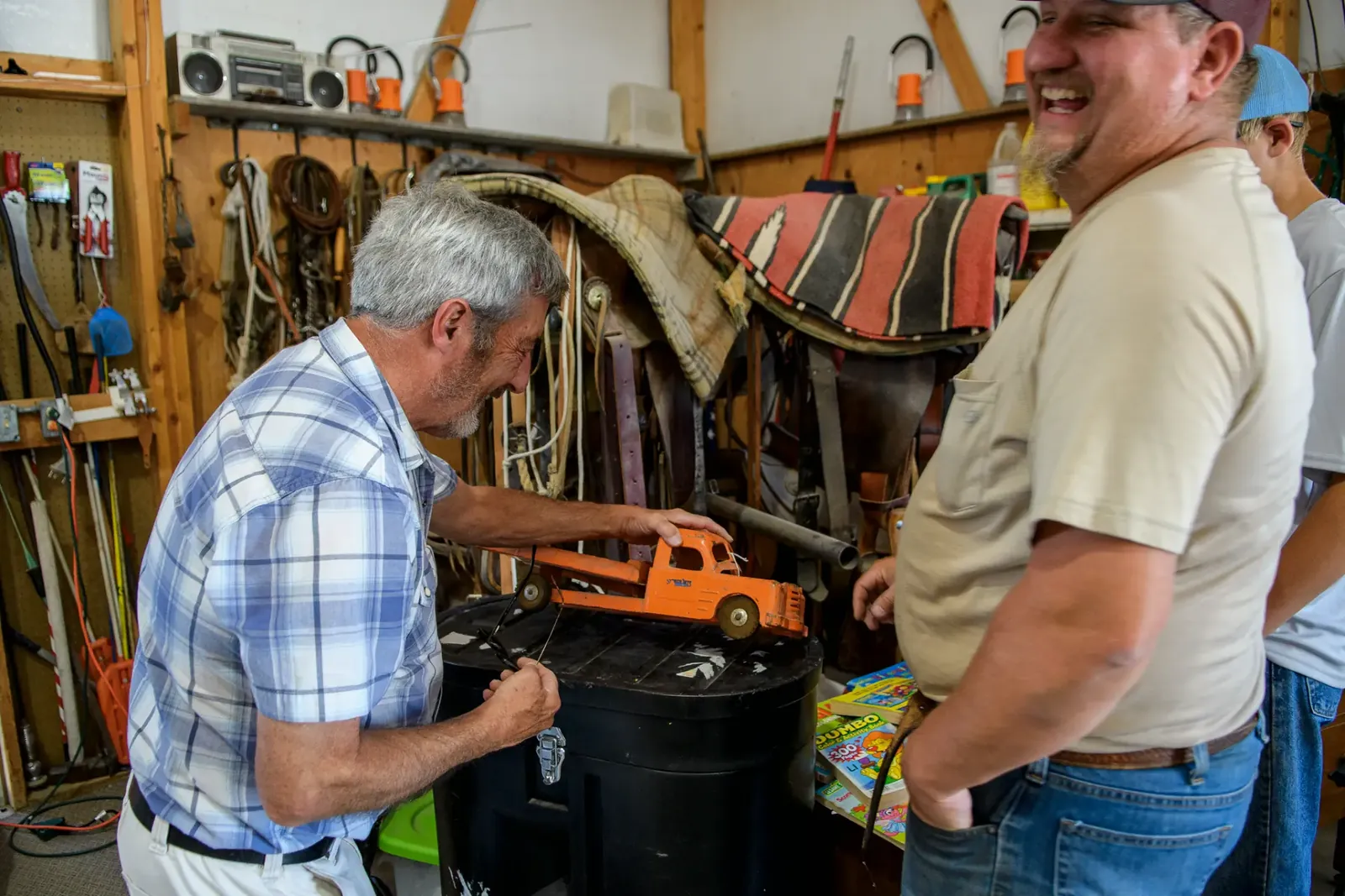 People sharing a laugh beside a toy truck in a workshop