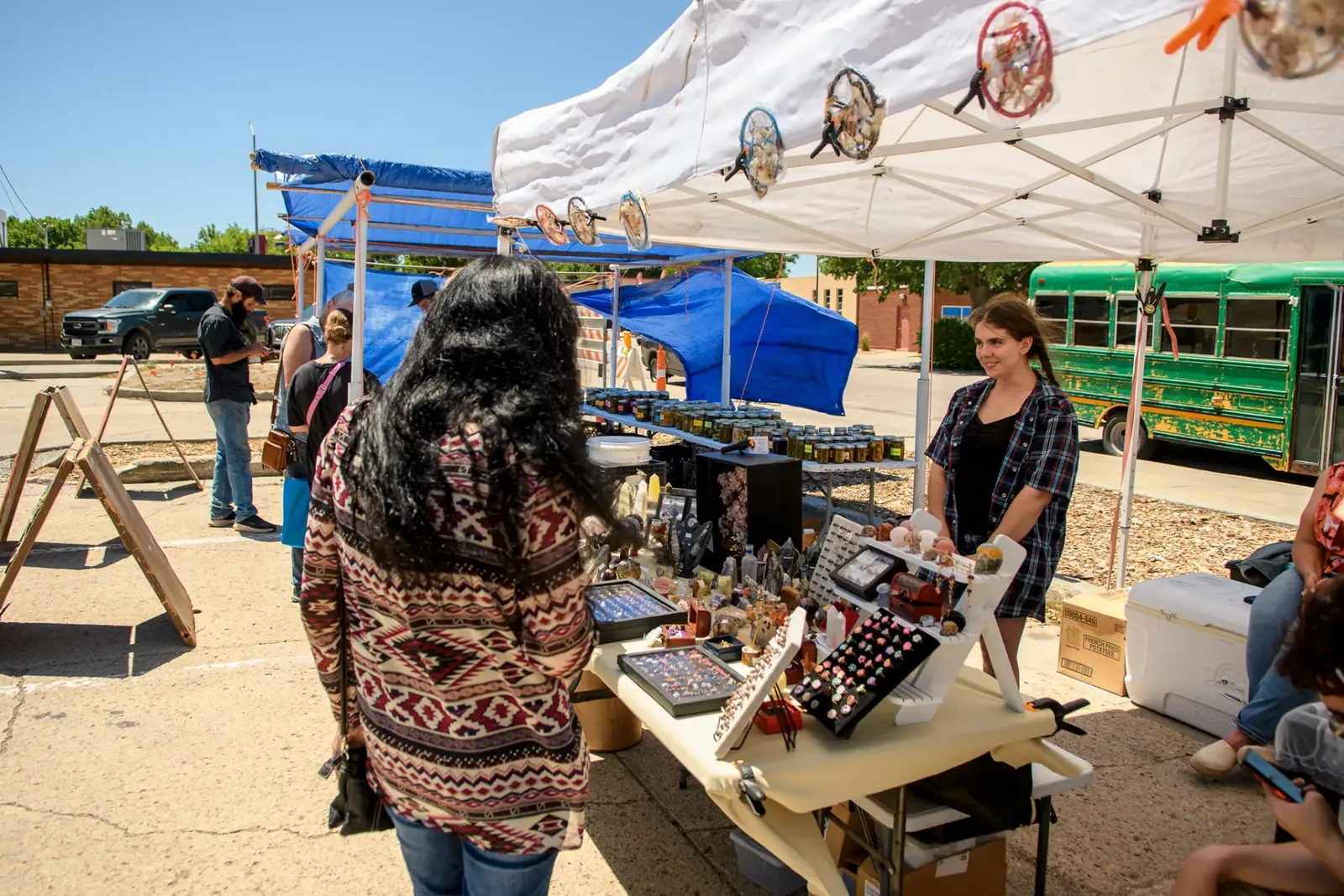 Shopper visiting an outdoor jewelry and craft market booth